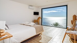 A bedroom with a bed, a TV, a large window with a view of the sea, and a chair. - Villa Sofia - Four Bedroom Villa, Sleeps 10 (Salobreña)