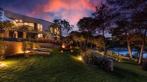 A modern house with a well-maintained lawn, outdoor seating, and a view of a body of water.