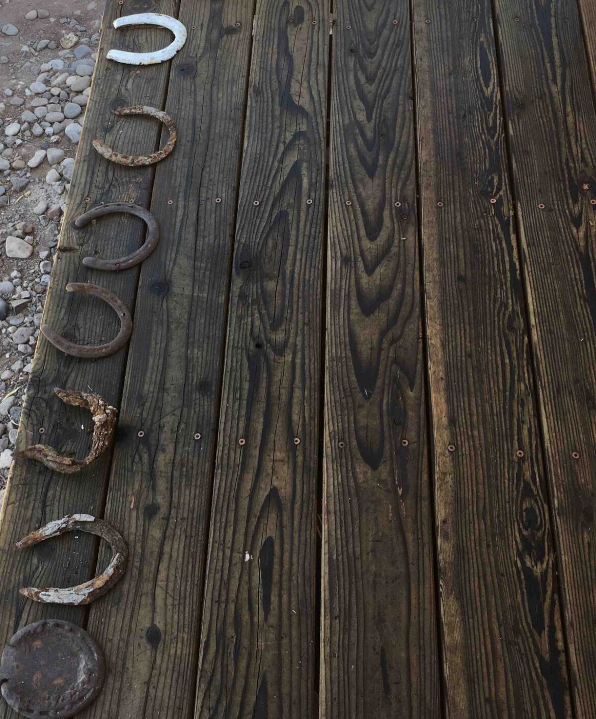 Une terrasse en bois avec des fers à cheval disposés en rangée.