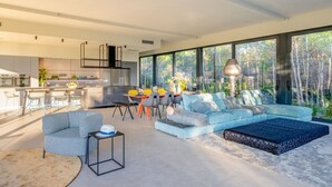 Un salon moderne comprenant un grand canapé, une table basse et un coin repas avec des chaises et une table.