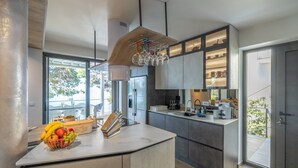 A modern kitchen with a central island, built-in appliances, and a large window providing natural light.