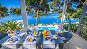 A dining table set with breakfast items, overlooking a pool and the sea.
