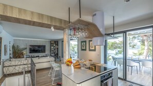 A modern kitchen with a central island, a dining area with a large table, and a living space with a TV and seating.