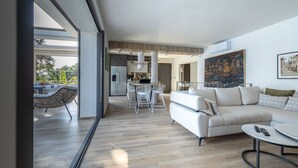A modern living room with a sofa, a coffee table, and a dining area with chairs and a table.
