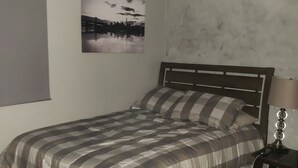 A bedroom with a bed, a nightstand, a lamp, a picture on the wall, and a window with blinds. - Private Gorgeous Cozy Modern home/5 min Drive from beach, righ across from park (Tijuana)