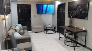 A living room with a sofa, a coffee table, a TV mounted on the wall, and a painting of a bridge. - Private Gorgeous Cozy Modern home/5 min Drive from beach, righ across from park (Tijuana)