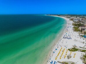 An aerial view of a beach with clear turquoise waters, a sandy shore, and numerous beach umbrellas. - Enchanting Coastal Ambiance & Breathtaking Sunsets (Siesta Key)