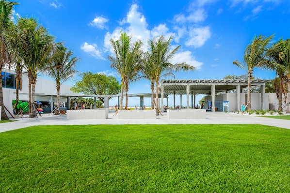 A modern building with a covered outdoor area, palm trees, and a well-maintained lawn. - Enchanting Coastal Ambiance & Breathtaking Sunsets (Siesta Key)
