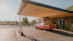 A vintage red car parked under a covered area with a brick building in the background. - Stay at a 1950s Classic Motel in Bozeman (Bozeman)