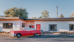 A red vintage car parked in front of a white building with a Coca-Cola sign, a Coca-Cola fountain, and a Coca-Cola truck parked outside. - Stay at a 1950s Classic Motel in Bozeman (Bozeman)