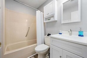 Une salle de bain avec une baignoire, des toilettes et un lavabo avec un miroir au-dessus.