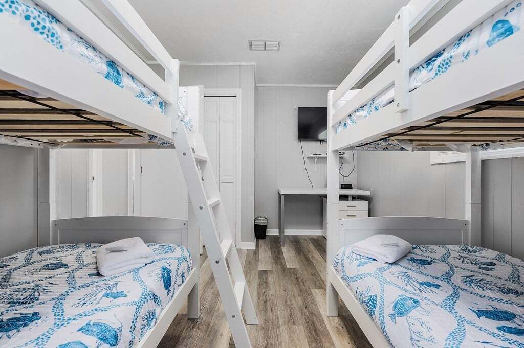 A bunk bed room with a desk and a TV.