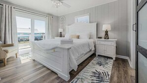 Camera da letto con un letto grande, una ventola a soffitto, un comodino, una sedia e vista all'esterno.