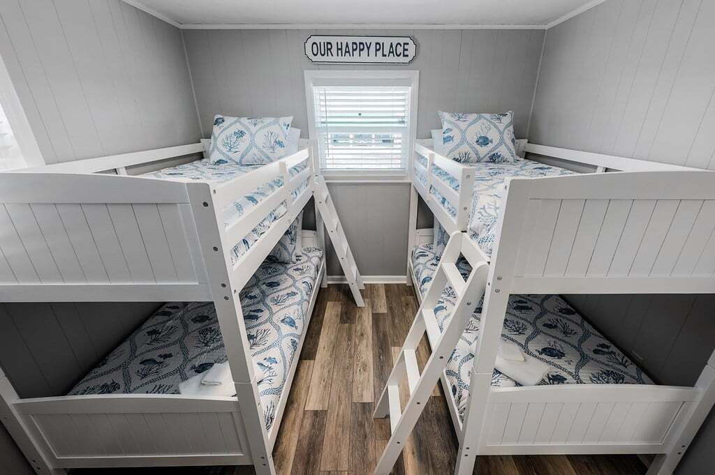 Una habitación con literas, una ventana con persianas y un cartel que dice 'OUR HAPPY PLACE'.