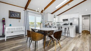 Una cucina moderna con mobili bianchi, un'isola centrale e un'area pranzo con tavolo e sedie rotonde.