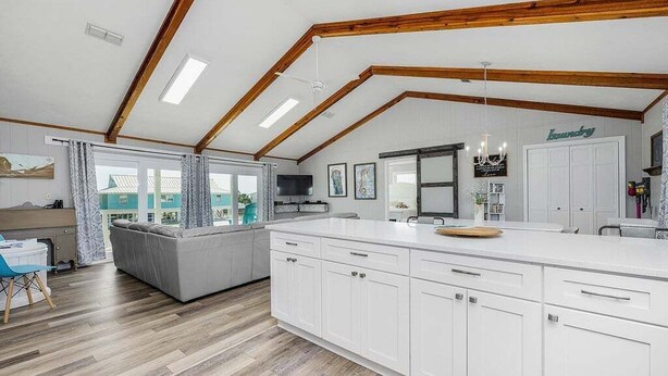 Una cucina moderna con pensili bianchi, un'isola grande e un'area pranzo con divano.