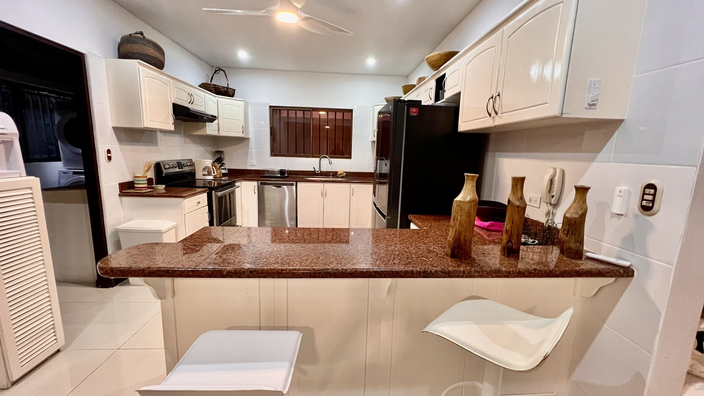 A modern kitchen with white cabinets, granite countertops, and a central island.