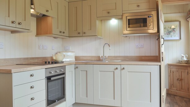 A kitchen with white cabinets, a microwave, a sink, and a stove.