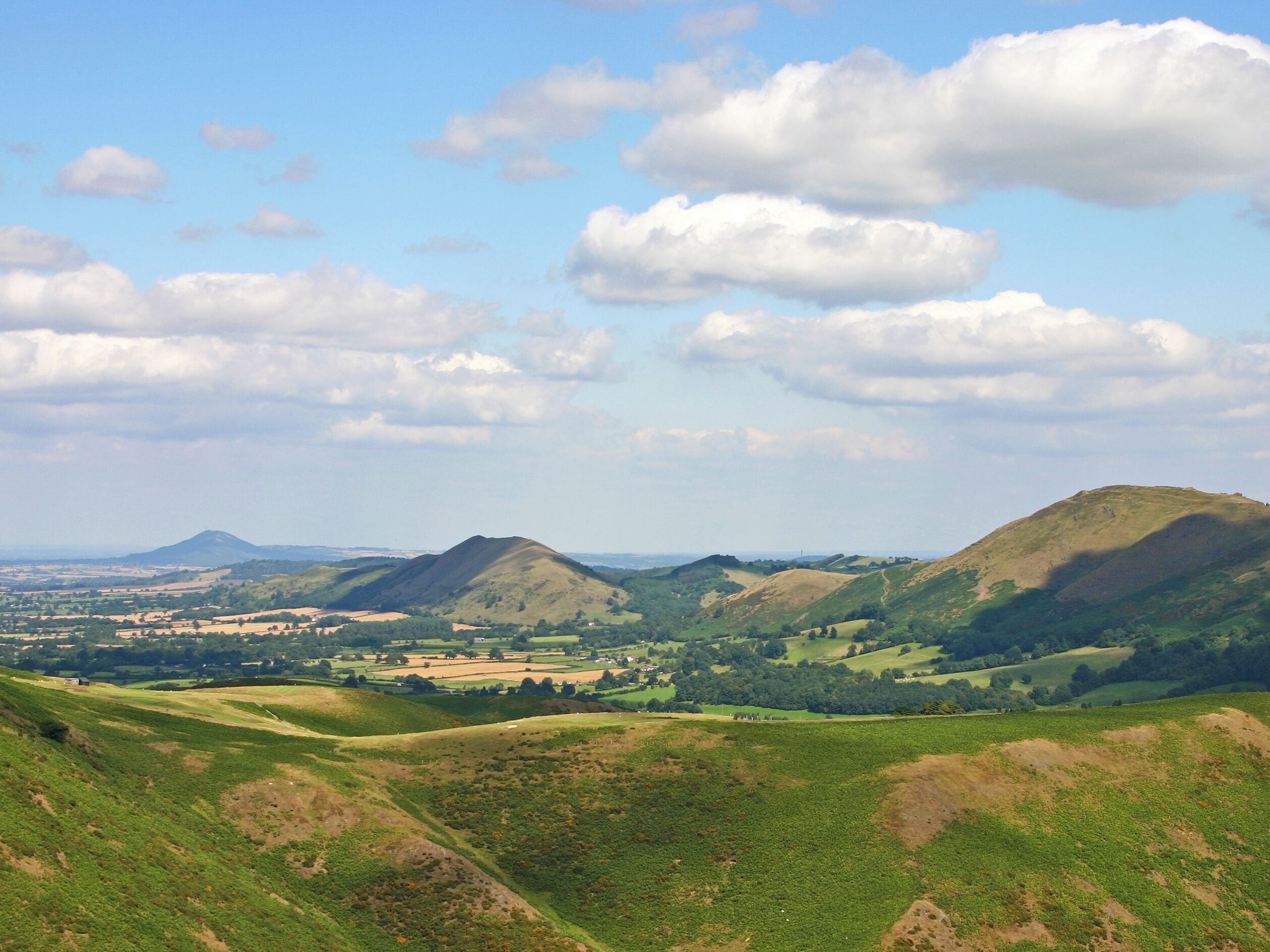 Eine Landschaft mit sanften Hügeln und einem Dorf in der Ferne.