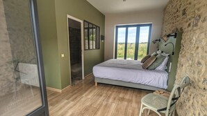 A bedroom with a bed, a chair, a window, and a door leading to a balcony.