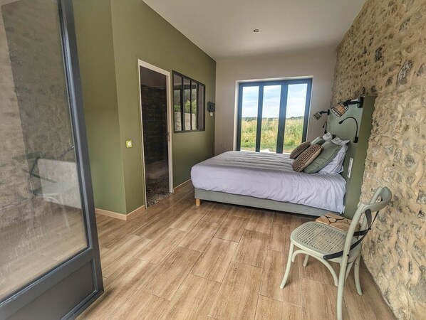 A bedroom with a bed, a chair, a window, and a door leading to a balcony. - Chambre sur Jardin Avec Jacuzzi Privatif L'été et Terrasse (Treuzy-Levelay)