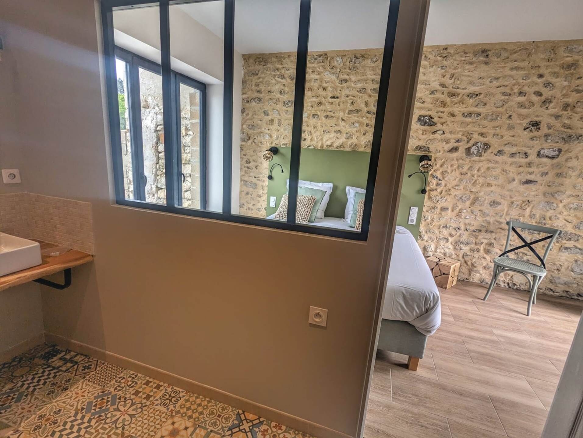 Ein Badezimmer mit Waschbecken, einem gemusterten Boden und einem Fenster.