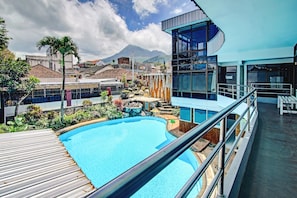 A modern building with a pool, surrounded by greenery and a view of mountains. - OYO Life 90077 Live Homestay (Batu)