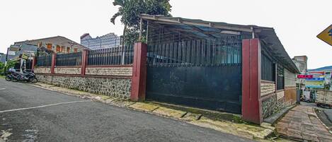 A gated building with a covered entrance, a stone wall, and a parked motorcycle.