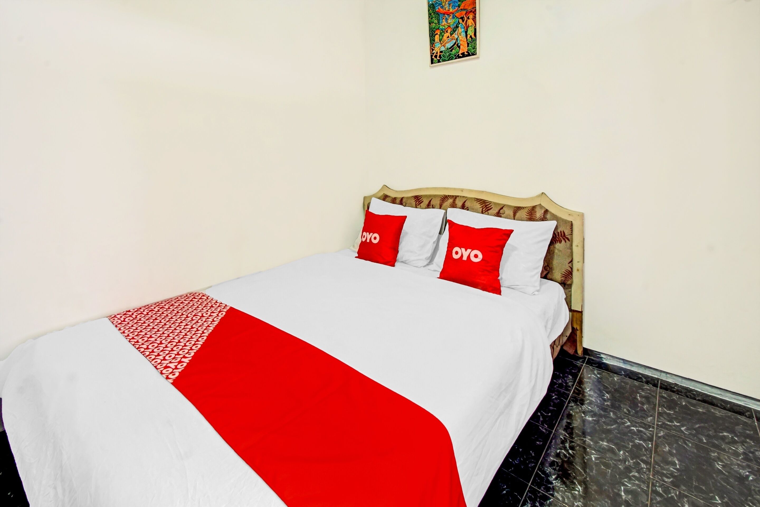 Un lit bien fait, recouvert d’une couette blanche et rouge, et agrémenté de deux oreillers portant le logo « OYO ».
