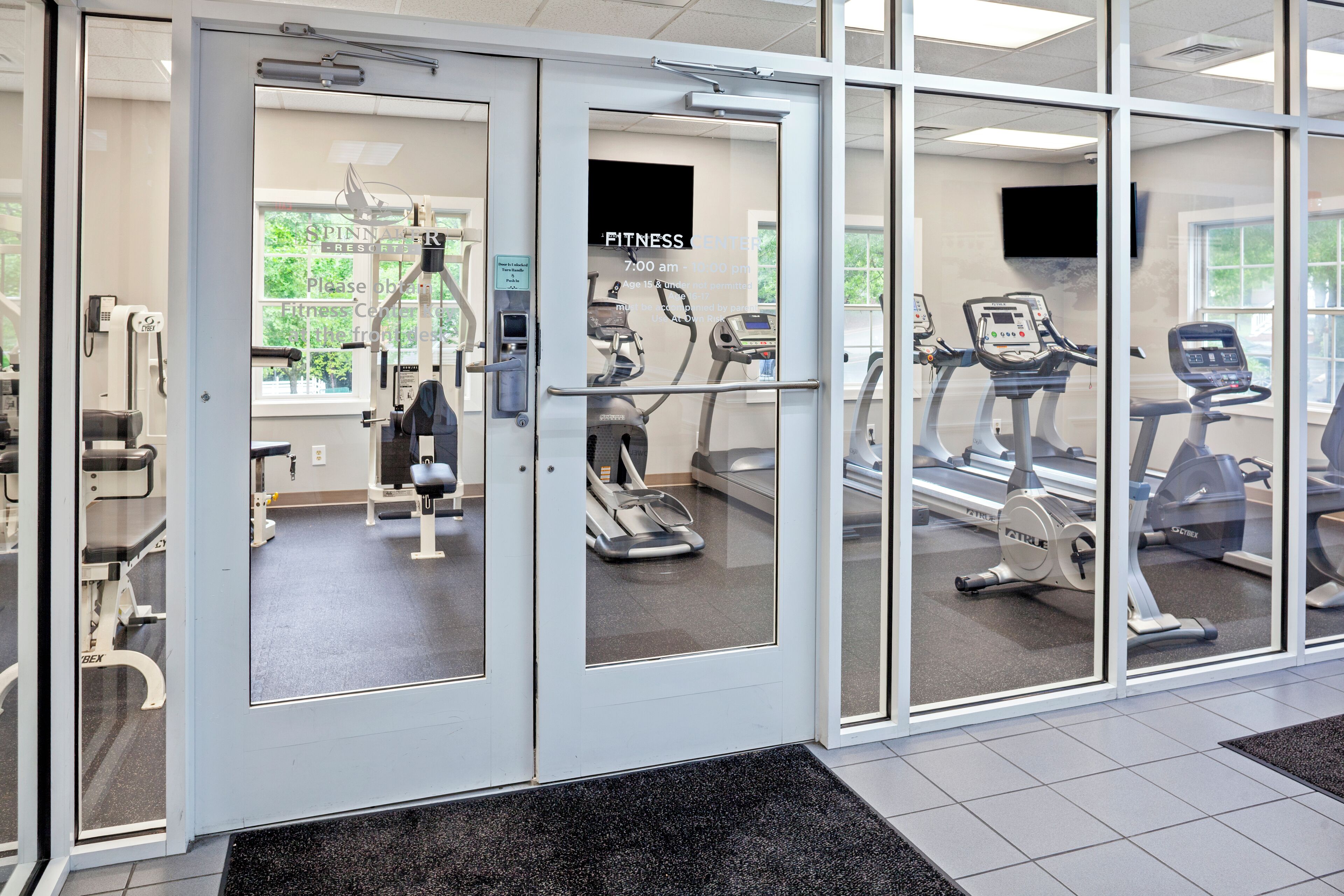 A fitness center with exercise equipment, a reception area, and a large window.