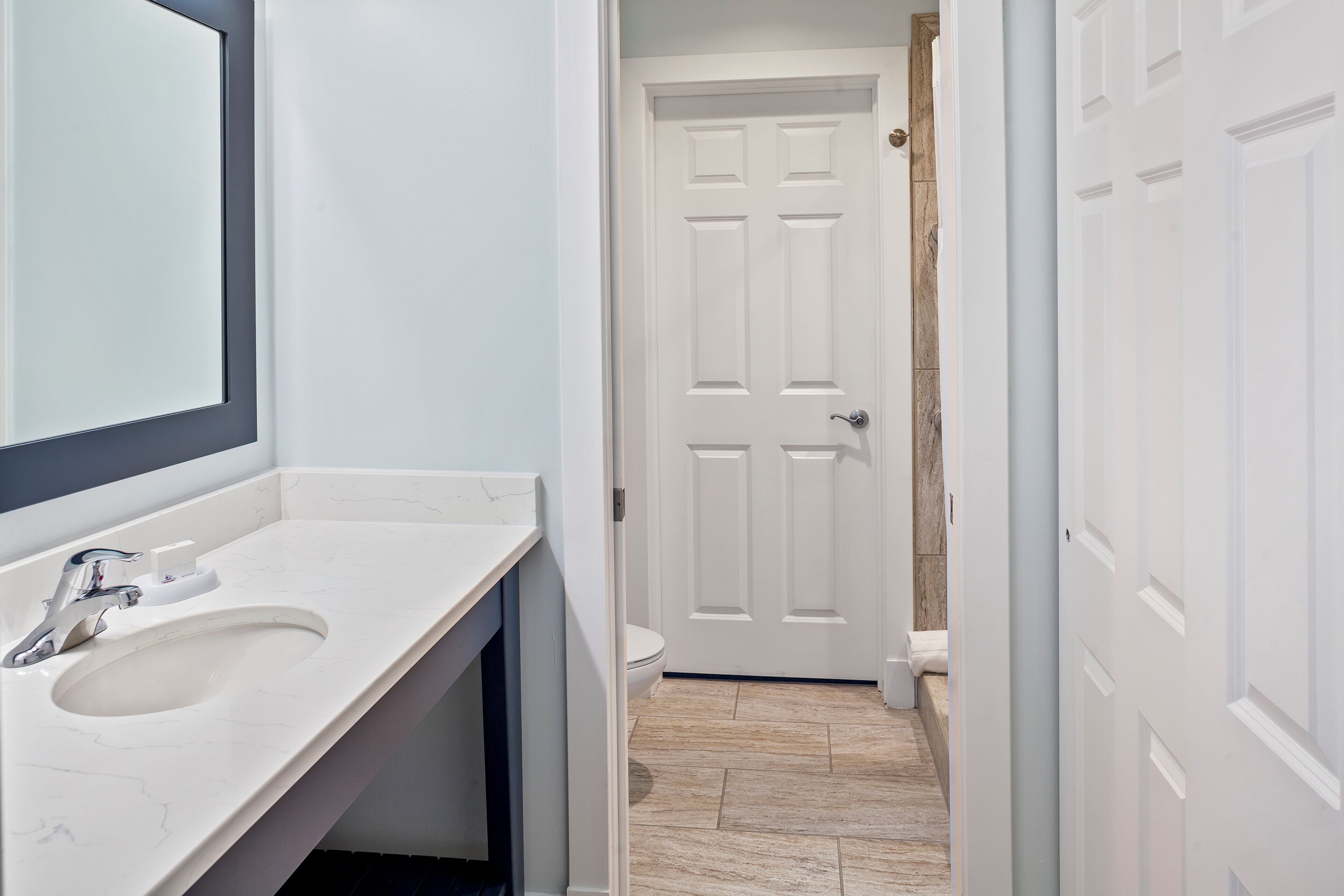 A bathroom with a white sink, mirror, and door.