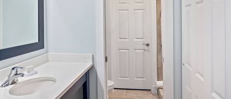 A bathroom with a white sink, mirror, and door.
