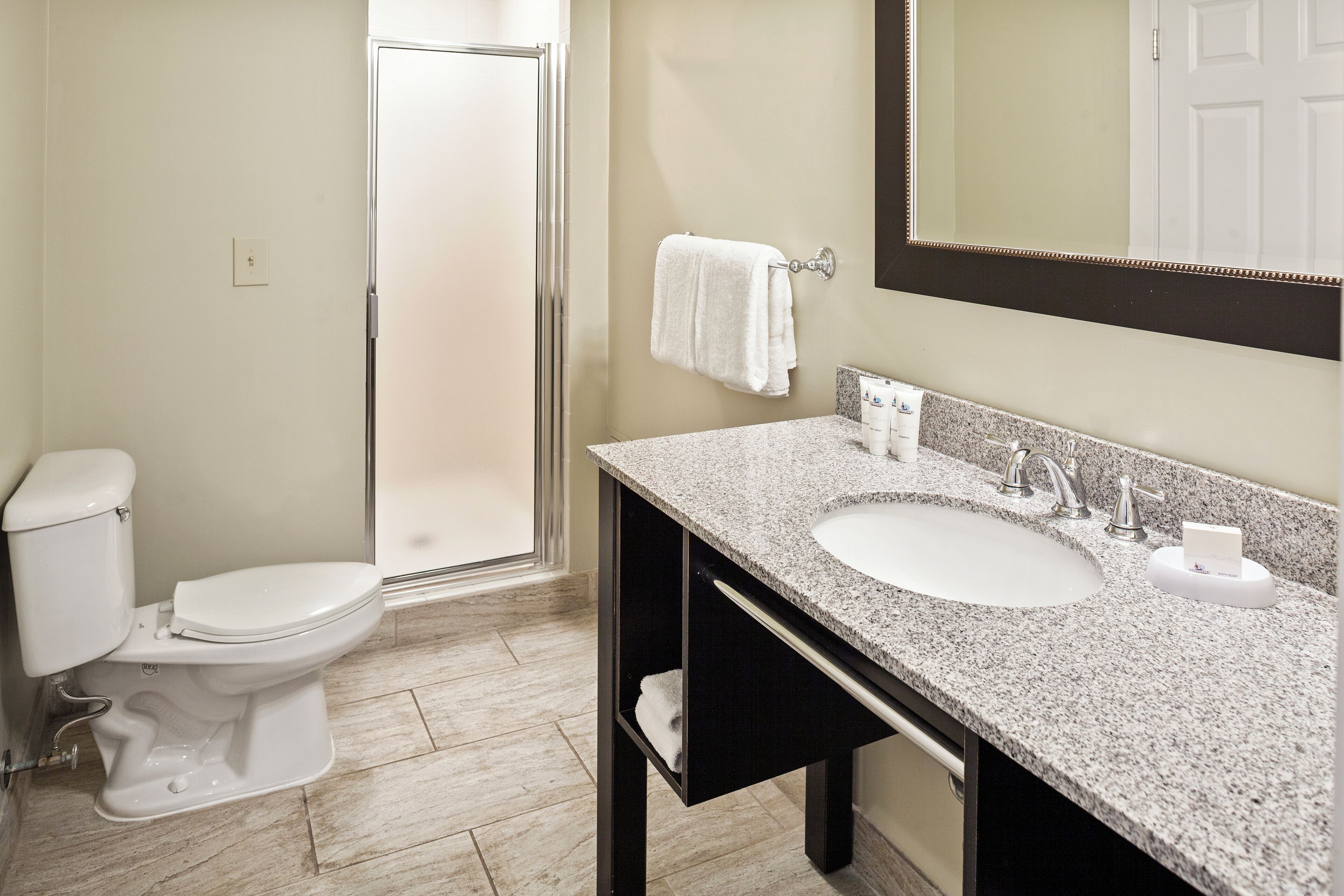 A bathroom with a toilet, sink, and mirror.