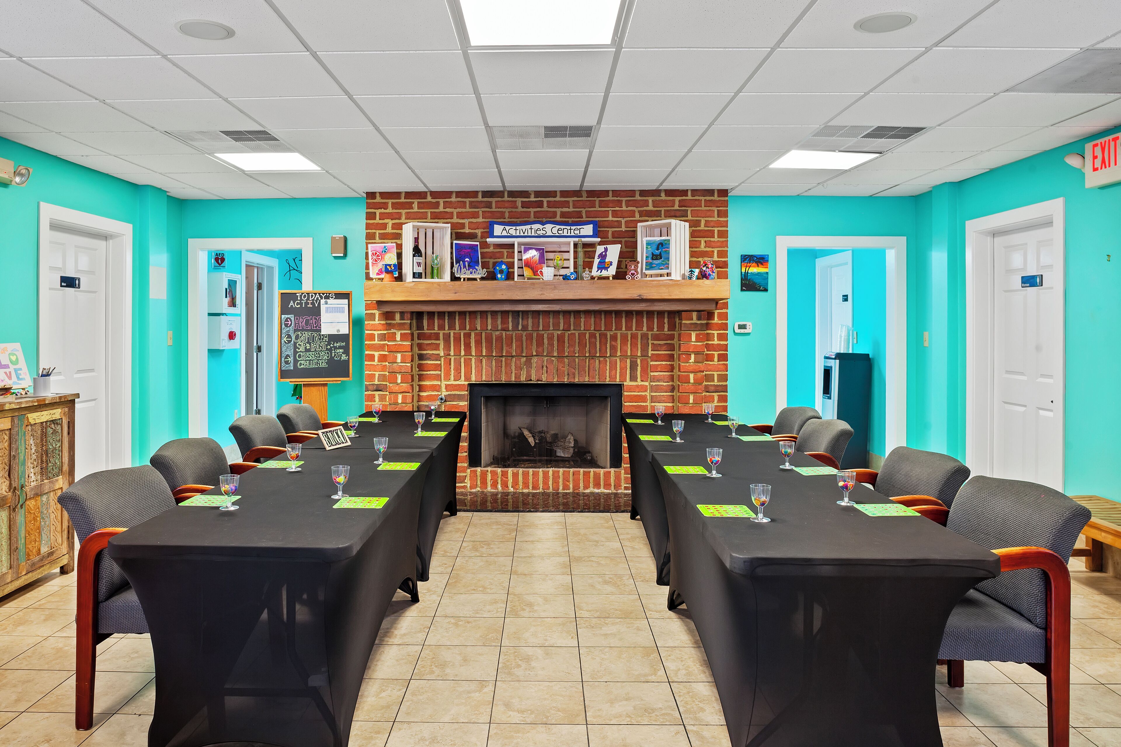 A conference room with a long table, chairs, a fireplace, and a sign reading "Activities Center".