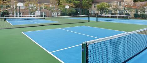 Cancha de tenis exterior con varias canchas, rodeada de edificios residenciales.