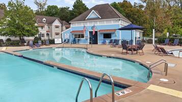 A swimming pool with lounge chairs and a building with American flags.