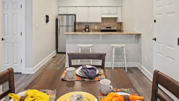 A compact kitchen with white cabinets, a stainless steel refrigerator, and a granite countertop.