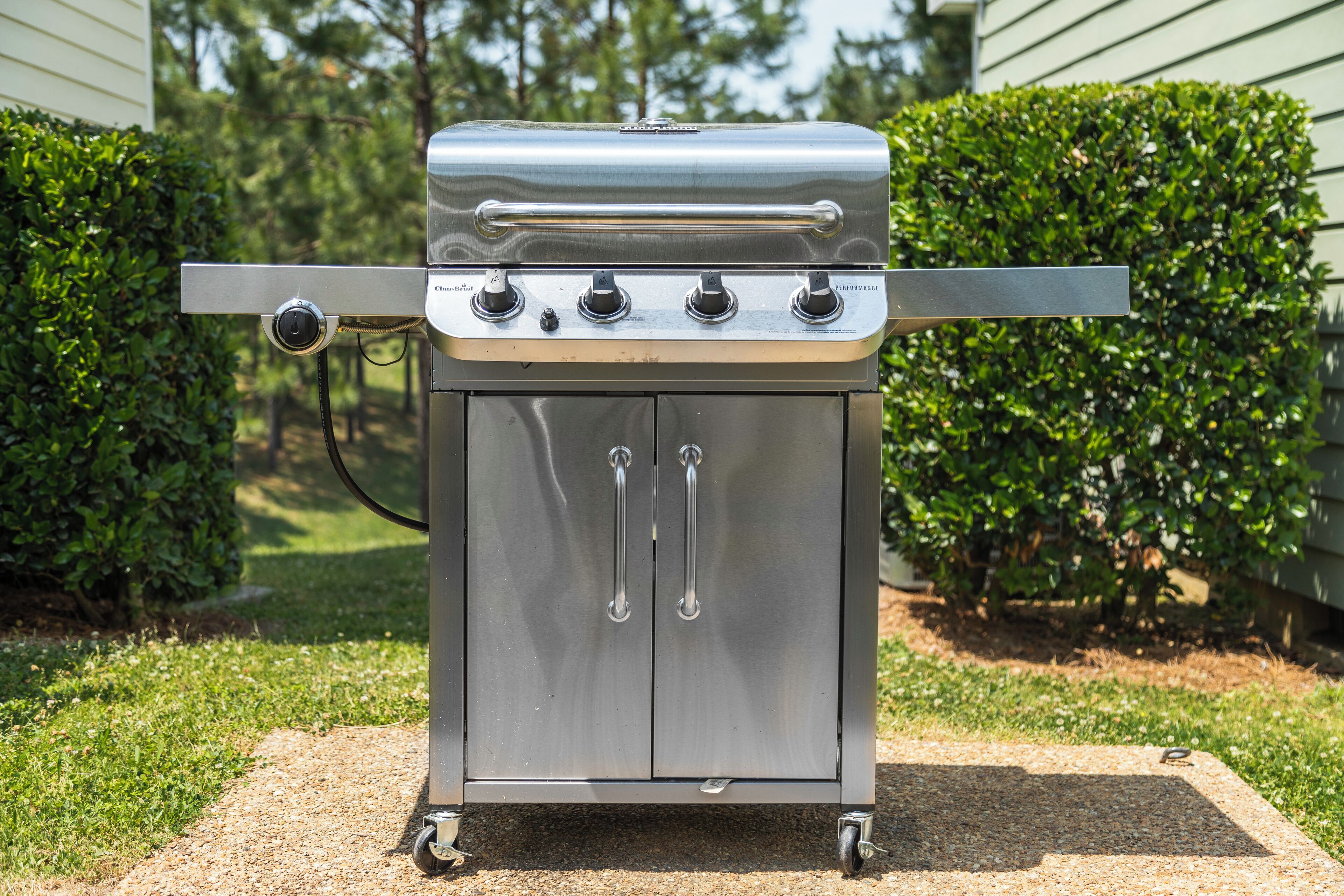 Una parrilla para barbacoa de acero inoxidable con cuatro quemadores, una repisa lateral y un panel de control.