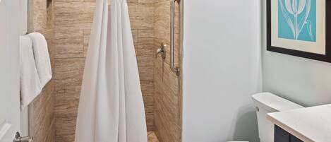 Een moderne badkamer met douche, toilet en wastafel.