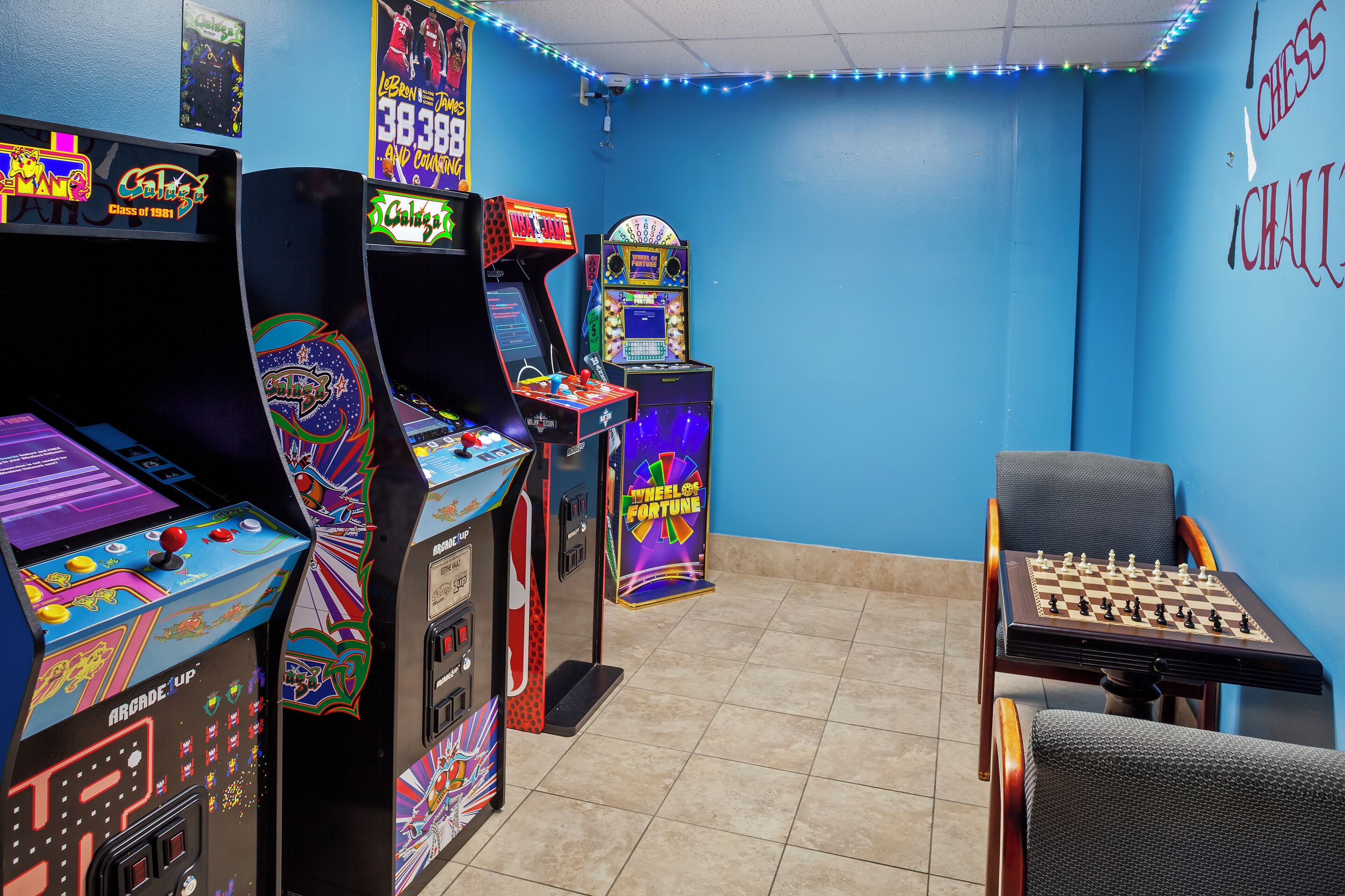 Een kamer met speelautomaten, een schaakbord en een blauwe muur met schaakdecoratie.