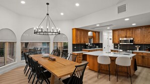 Una cocina moderna con armarios de madera, una isla grande y un comedor con mesa y sillas de madera.