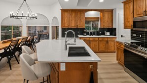 Una cocina moderna con armarios de madera, una isla central con un lavamanos y una estufa grande.