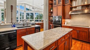 Eine moderne Küche mit Granit Arbeitsplatten, Holzschränken und Edelstahlgeräten.