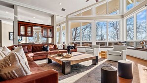 Ein geräumiges Wohnzimmer mit großem Fenster, Kamin und hohen Decken.