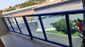En balkon med udsigt til en parkeringsplads og en bygning med en grå facade.