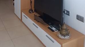 En moderne stue med et fladskærms-tv, en tv-reol i træ og dekorative genstande.