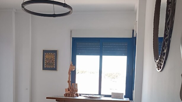 En stue med blå sofa, træbord og hængende lampe.