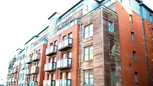 Un edificio residencial de varios pisos con balcones, grandes ventanales y fachada de ladrillo.