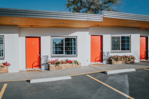 A building with three orange doors, each with a window above. There are flower planters in front of each door. - Retro Motel in Bozeman Montana (Bozeman)