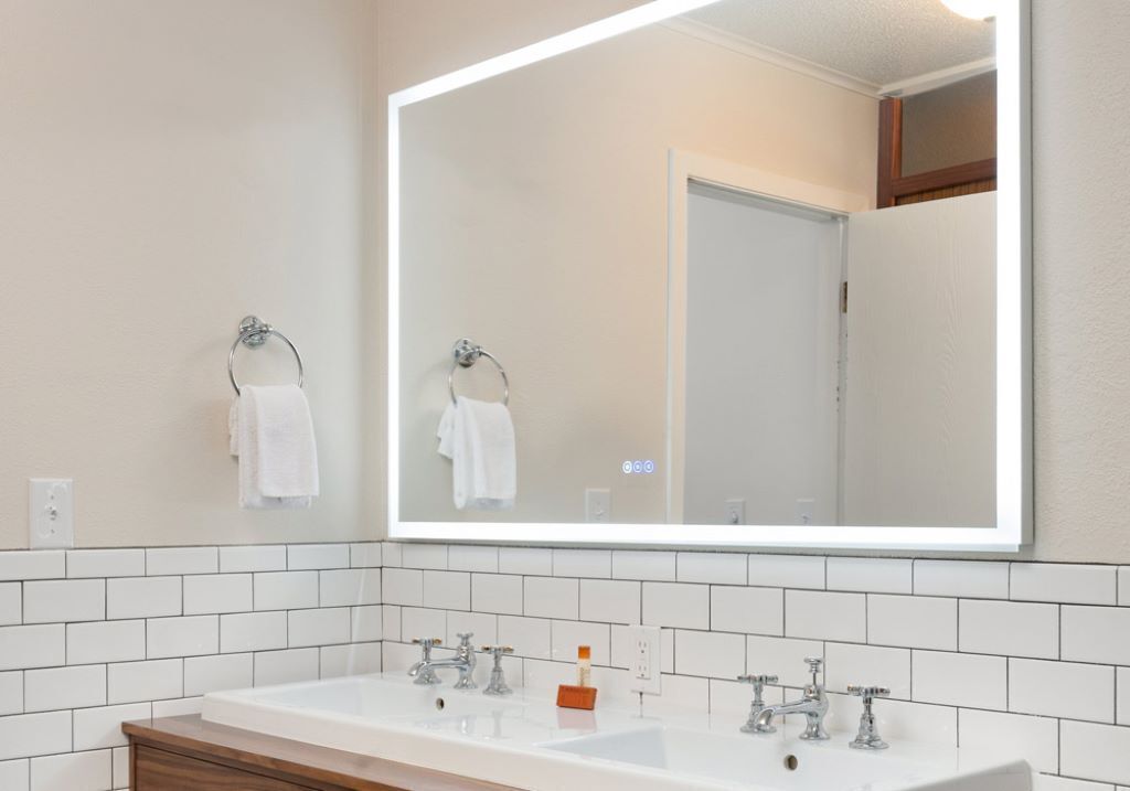 Un baño con un espejo grande, dos lavamanos y un mueble de tocador de madera.